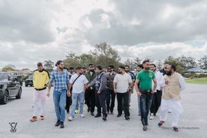 A group of people walking in a line outdoors on a cloudy day during a guided tour or event.