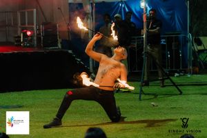 Fire performers create a dramatic display with flaming batons during a nighttime outdoor performance.