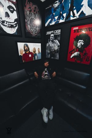 A dark room with music posters and album artwork displayed on walls, shot from a low angle showing sneakers.