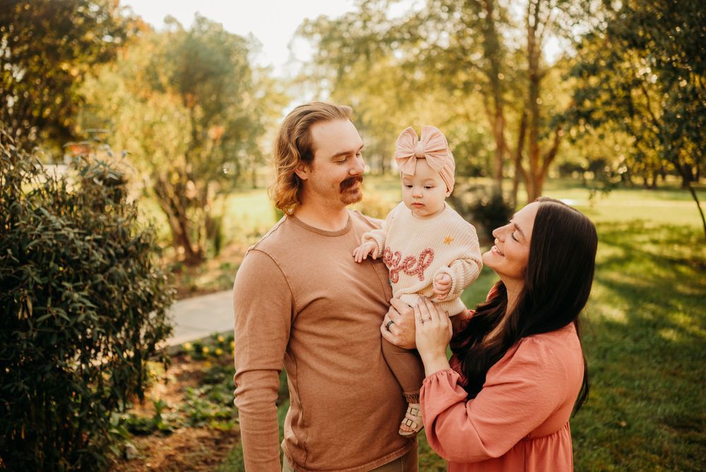Family of 3 takes family photos as parents each look fondly at their infant daughter in admiration. Photo by Disney Magic Photography