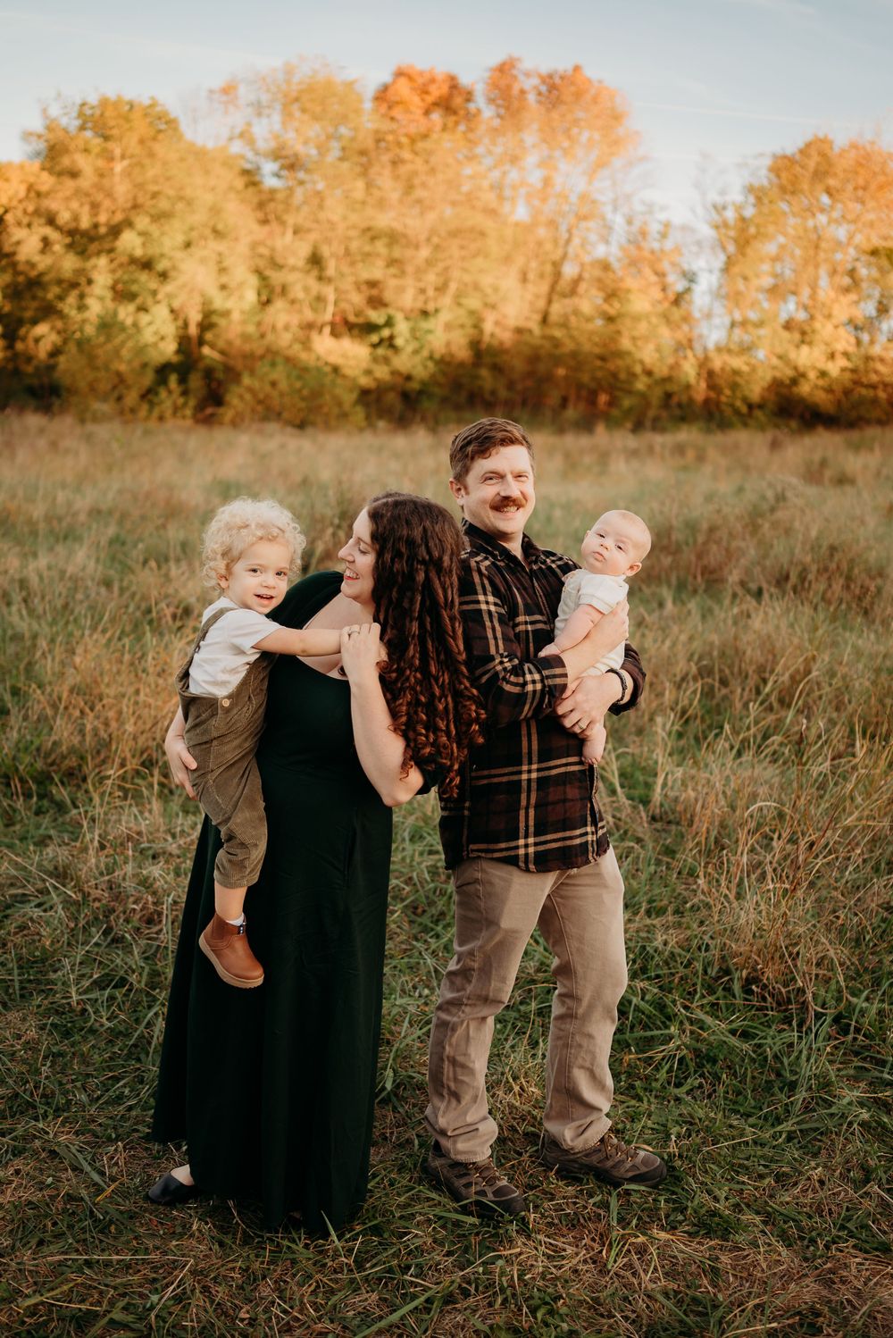 Fort Campbell military family smiles while taking photos in a field in Clarksville, Tennessee. Photo by Disney Magic Photography.