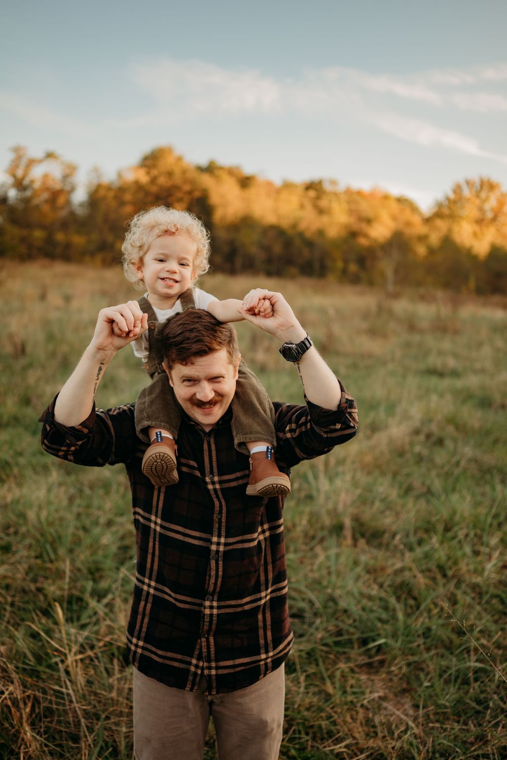 Toddler boy rides lovingly on dad's shoulders as both smile and laugh. Photo by Disney Magic Photography Clarksville, TN.