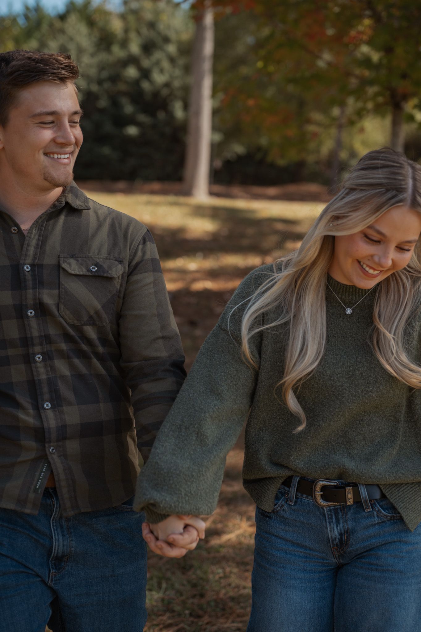 Casual couple in plaid and denim share laughs during an outdoor photo session.