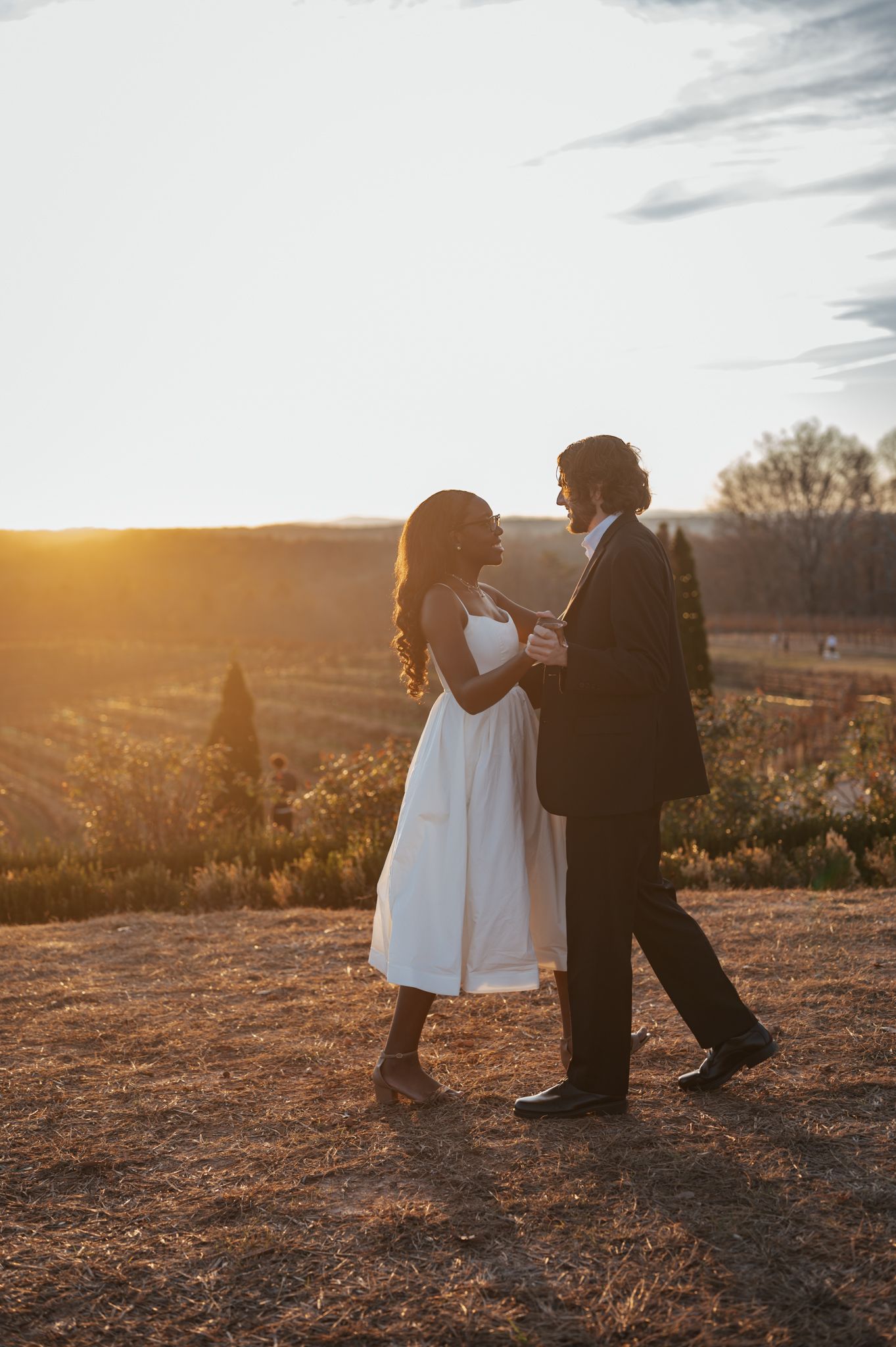 Silhouetted couple dancing at sunset in formal attire.