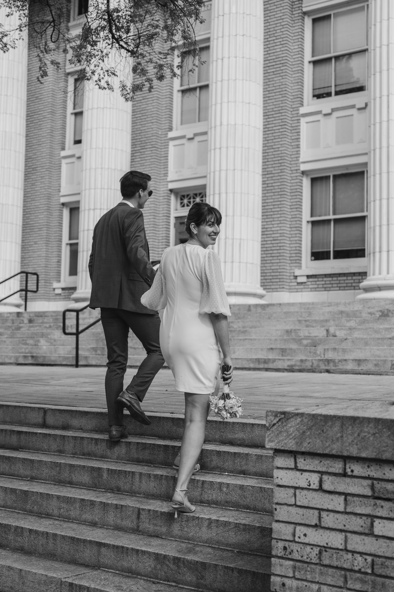 Black and white photo sequence of couple ascending brick steps by classical building.