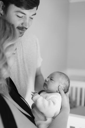 Sioux City, Iowa photographer. Black and white portrait of a father with mustache gently cradling his sleeping newborn baby.