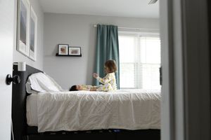 Sioux City, Iowa photographer. Young child sitting on a bed interacting with a newborn baby in a softly lit bedroom.