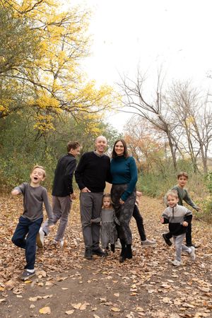 Sioux City, Iowa photographer. Family of six posing playfully on a leaf-covered autumn trail surrounded by fall foliage.