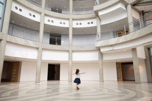 Sioux City, Iowa photographer. Young girl twirling alone in a large circular rotunda with white walls and multiple balcony levels above.