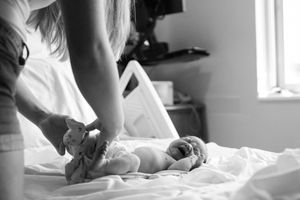 Sioux City, Iowa photographer. Black and white photo of a mother tending to her newborn baby on a hospital bed after delivery.