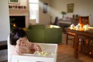 Sioux City, Iowa photographer. Baby girl in pink outfit eating in a white high chair in a cozy living room.