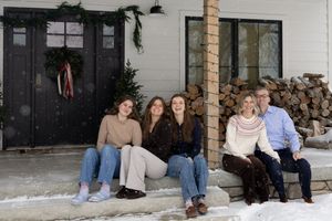 Sioux City, Iowa photographer. Family of five posing on snowy front porch steps of white farmhouse.