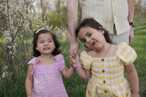 Sioux City, Iowa photographer. Two young sisters in pink and yellow dresses holding hands in a garden.