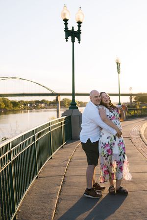 Sioux City, Iowa photographer. Happy couple embracing on a riverside promenade at golden hour sunset.