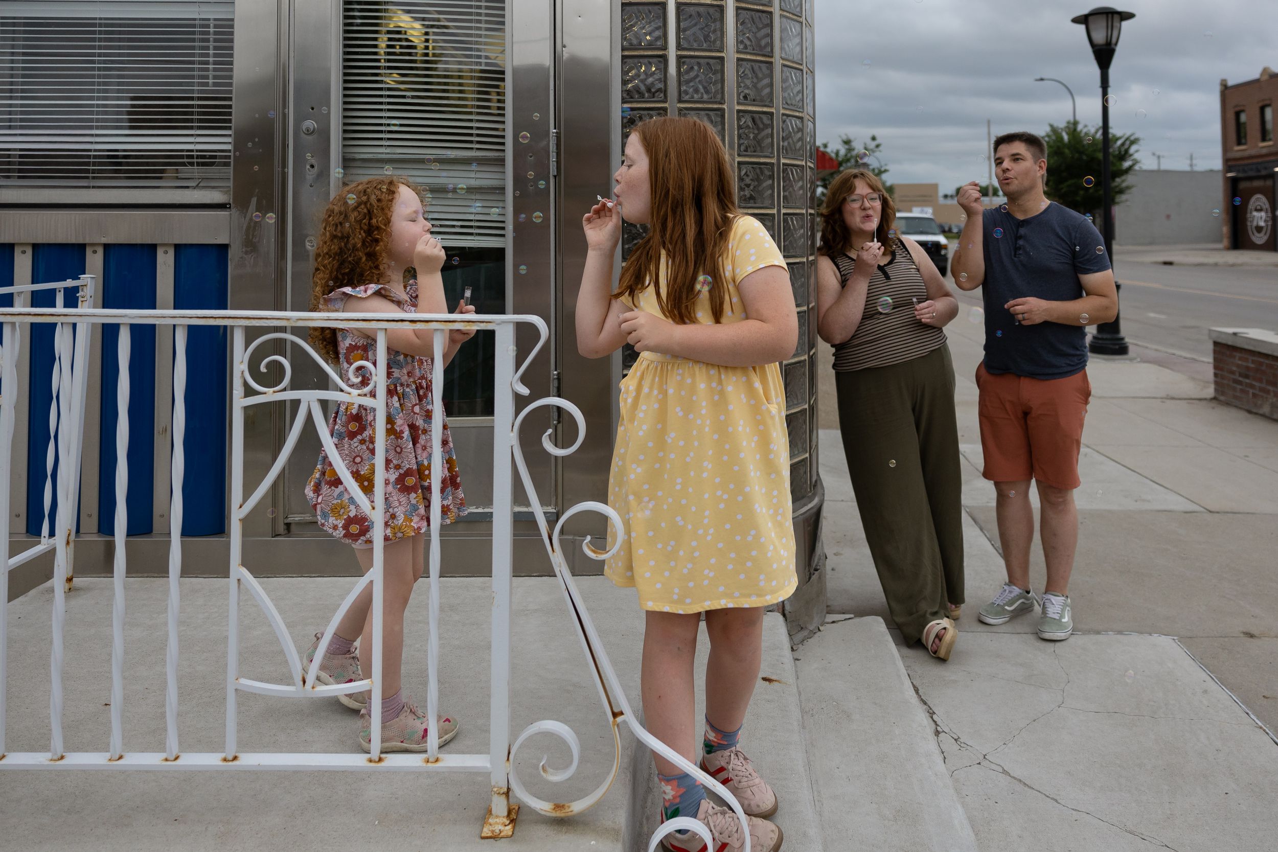 Group of young people enjoying ice cream outside a blue and white building on a sunny day.