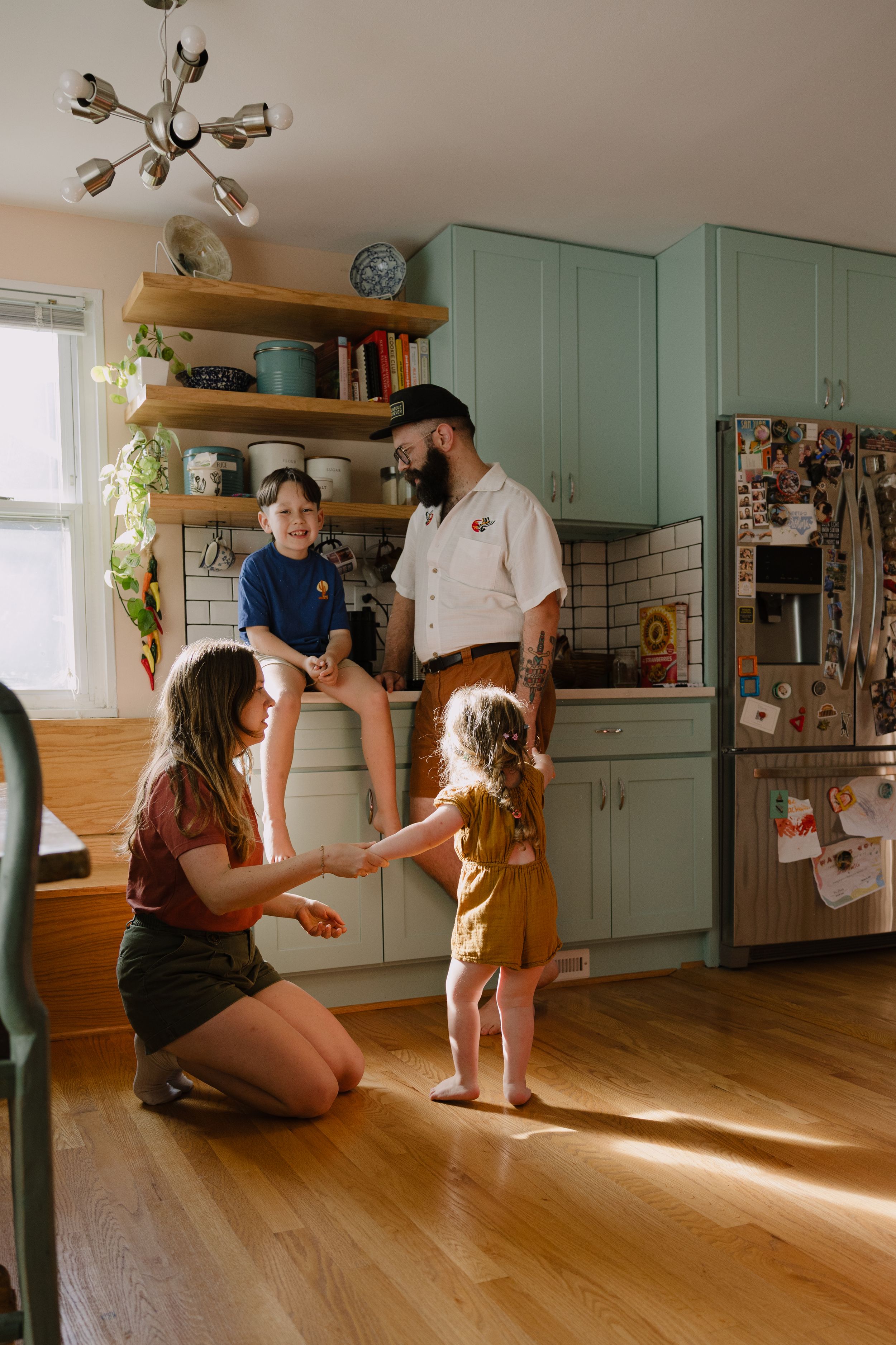 Sioux City, Iowa photographer. Family of four enjoying time together in a bright kitchen with mint green cabinets.