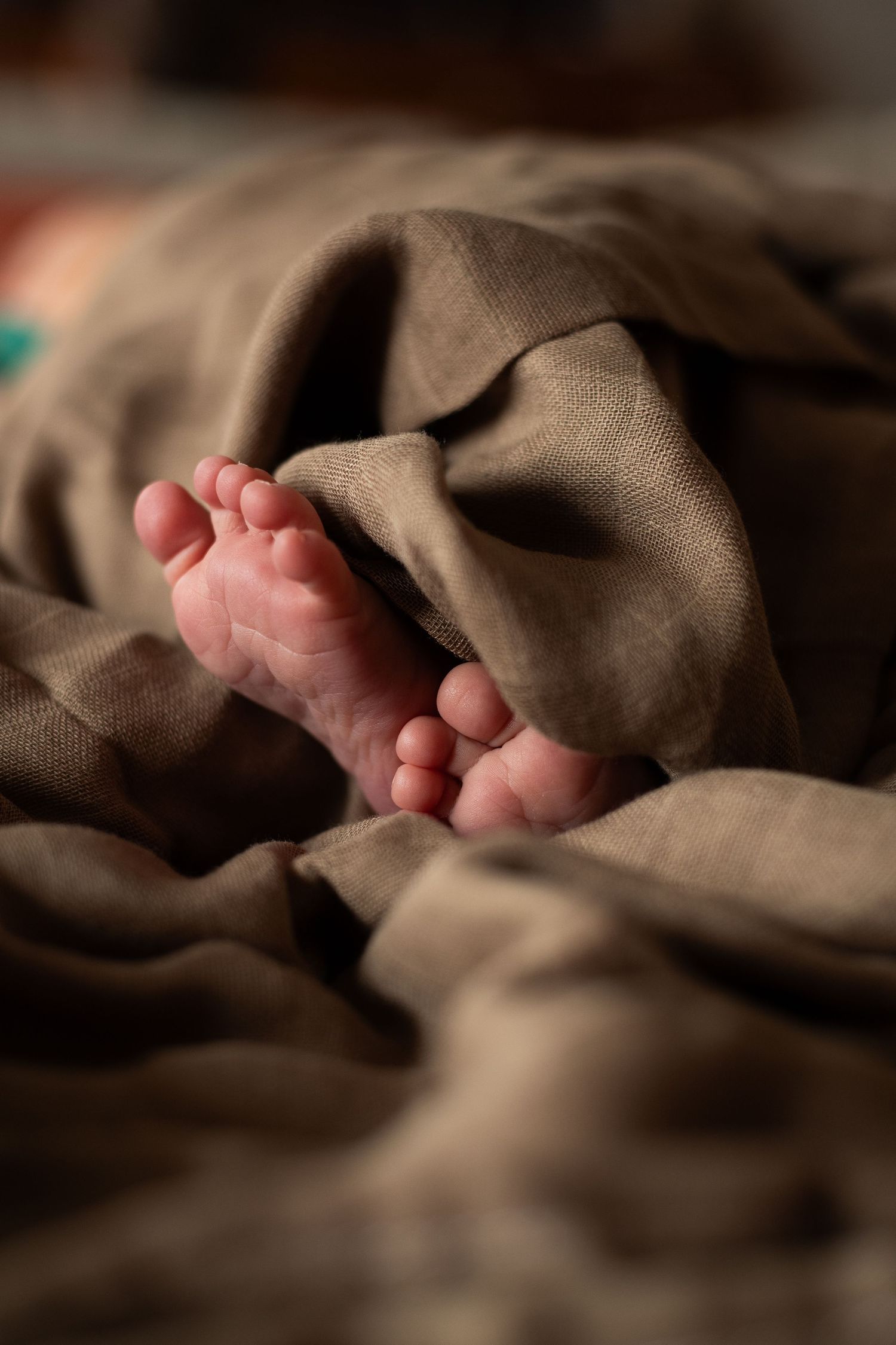 A dark and cozy photo capturing the small feet and details of a newborn