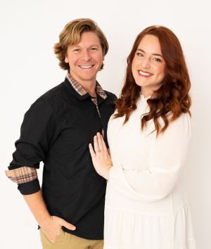 Happy couple poses playfully in studio against white background wearing black and white casual outfits.