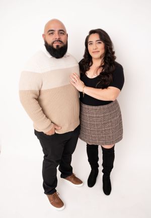 Overhead view of stylish couple in casual sweaters posing on white background.