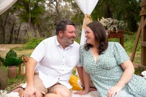 Couple sharing intimate moments at an outdoor event with white draped backdrop.