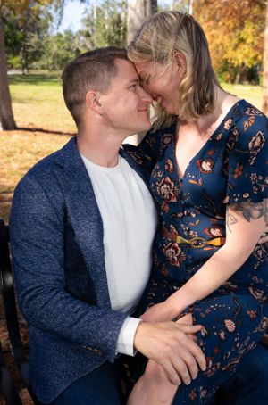 Intimate autumn portrait session with couple in navy and floral outfits under fall foliage.