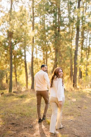 Romantic couple photoshoot in a sun-drenched forest during golden hour.