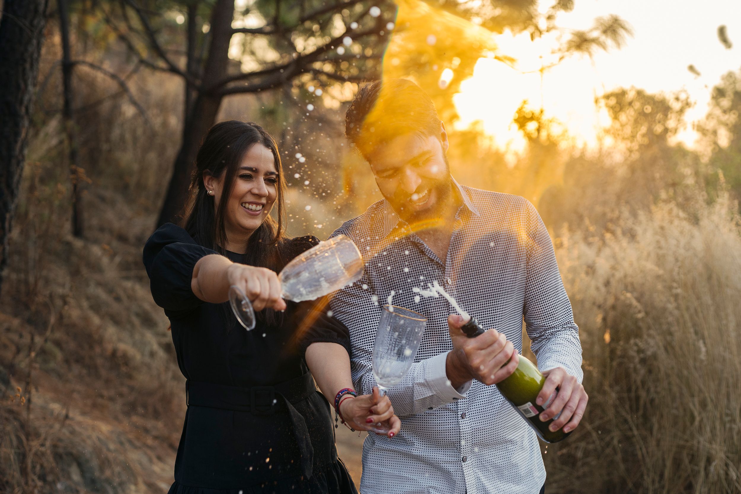 Couple sharing intimate moments during a golden sunset photoshoot in a field.