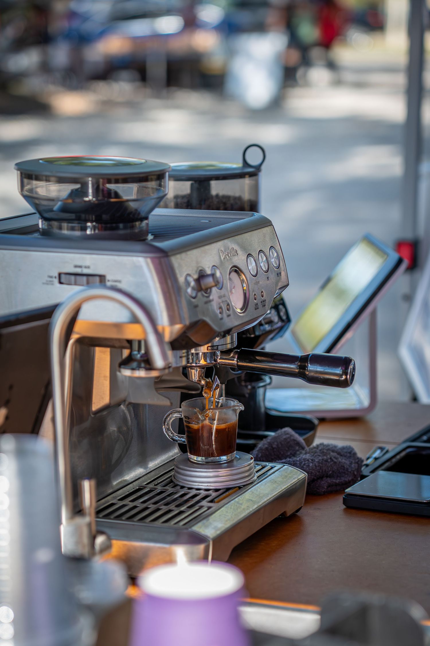 An espresso machine pouring coffee into a cup with steam rising in soft focus.