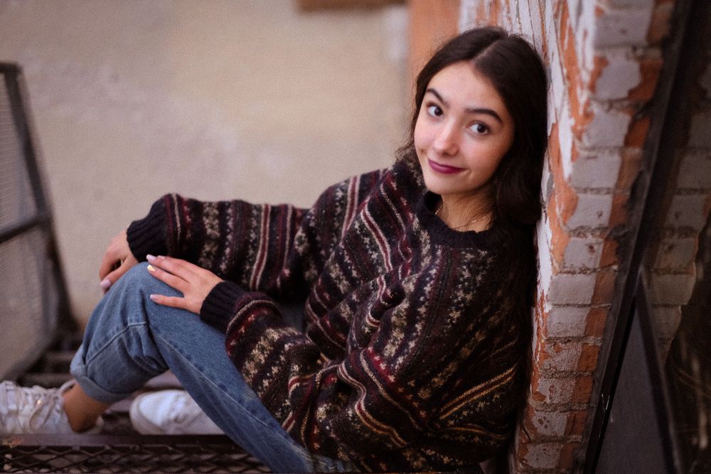 A person in a black lace dress poses against a brick wall backdrop in various candid shots.