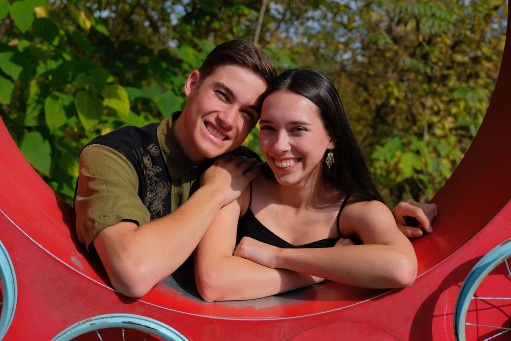 A couple shares a romantic moment together on a red background in a series of candid photos.