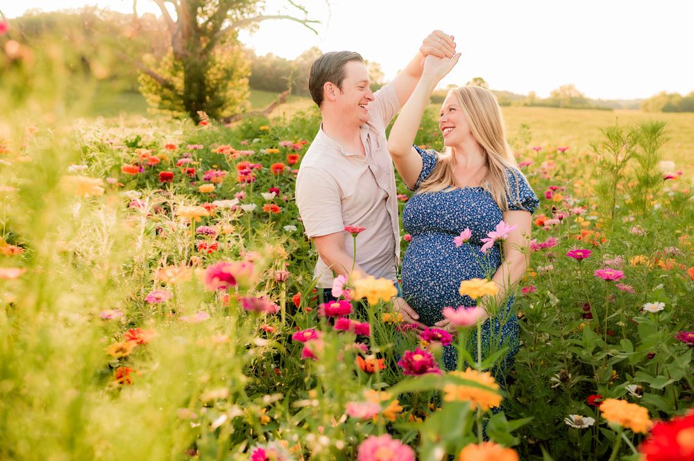 Couple sharing intimate moment among colorful wildflowers in golden sunlight.