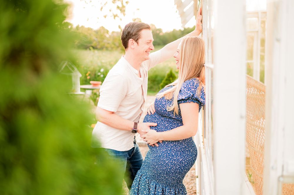 Couple posing together against white wall in outdoor garden setting.