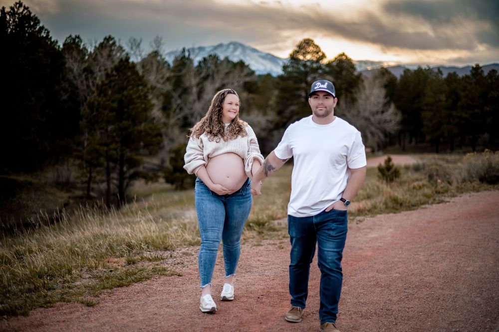 A couple walks together on a mountain trail during golden hour.