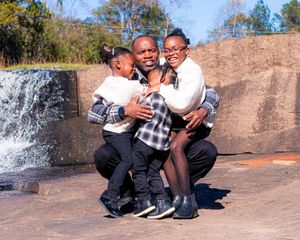 A family group shares a joyful moment by a waterfall.