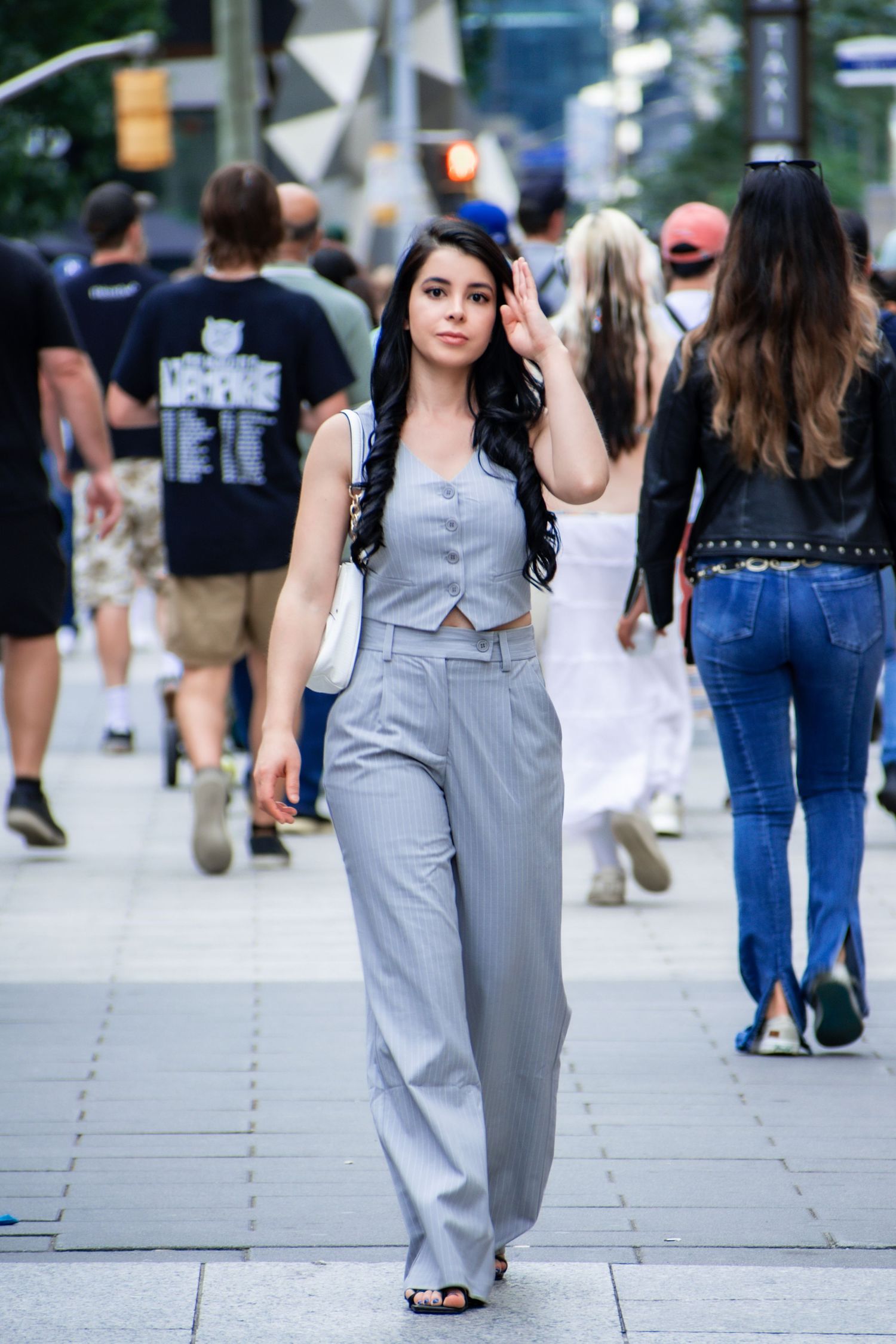 Stylish young woman in gray wide-leg pants walking confidently on a busy urban sidewalk. Toronto GTA