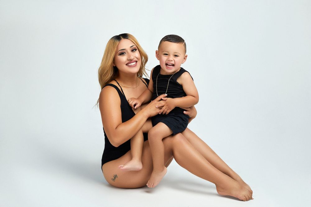 Family in black outfits posing together on light studio background.