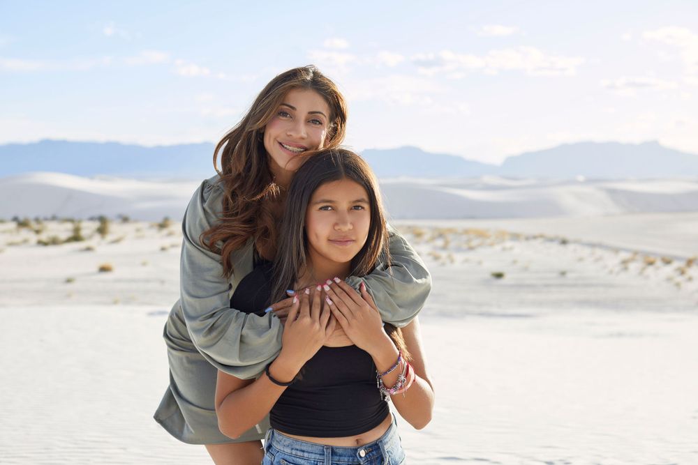 Friends enjoying a playful moment together on sandy white dunes.