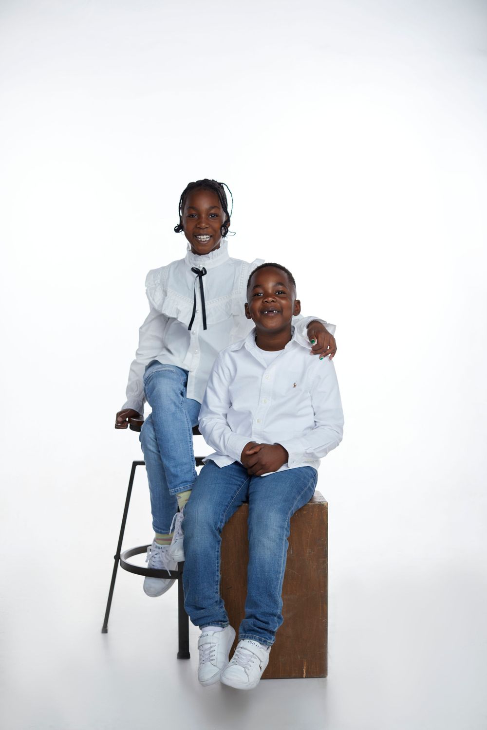 Minimalist portrait session featuring white shirts and blue jeans against a bright background.