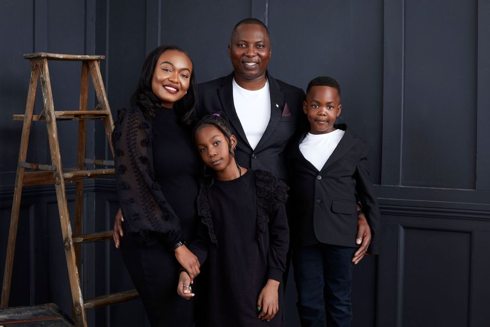 Candid family moments captured in a studio with dark blue walls and wooden accents.
