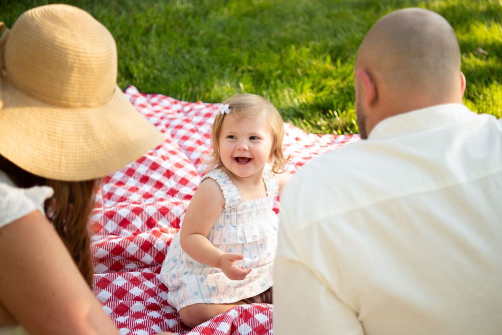 Happy family moment on red checkered picnic blanket in sunny backyard.