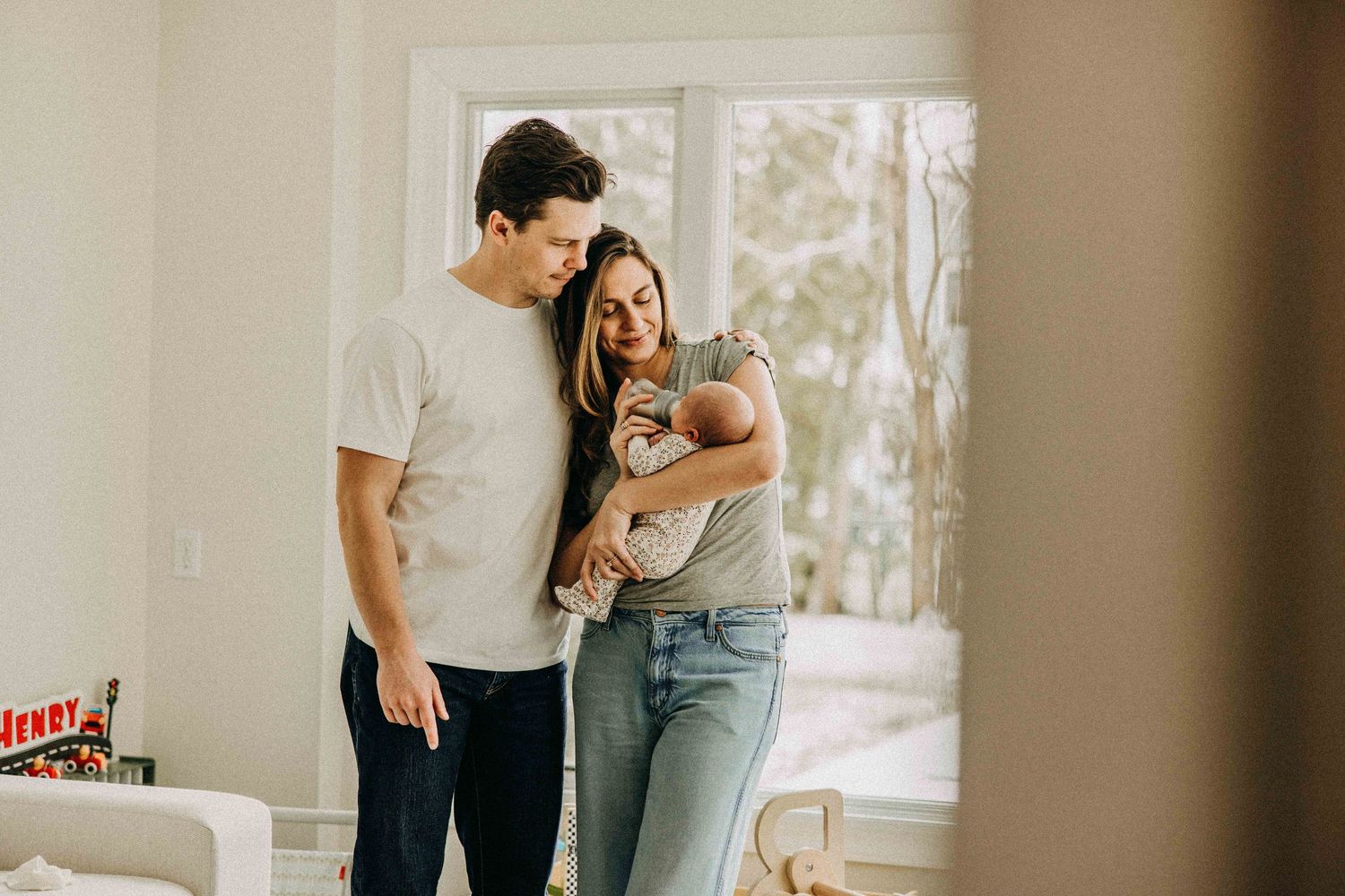 Young family posing together in modern living room with natural light.