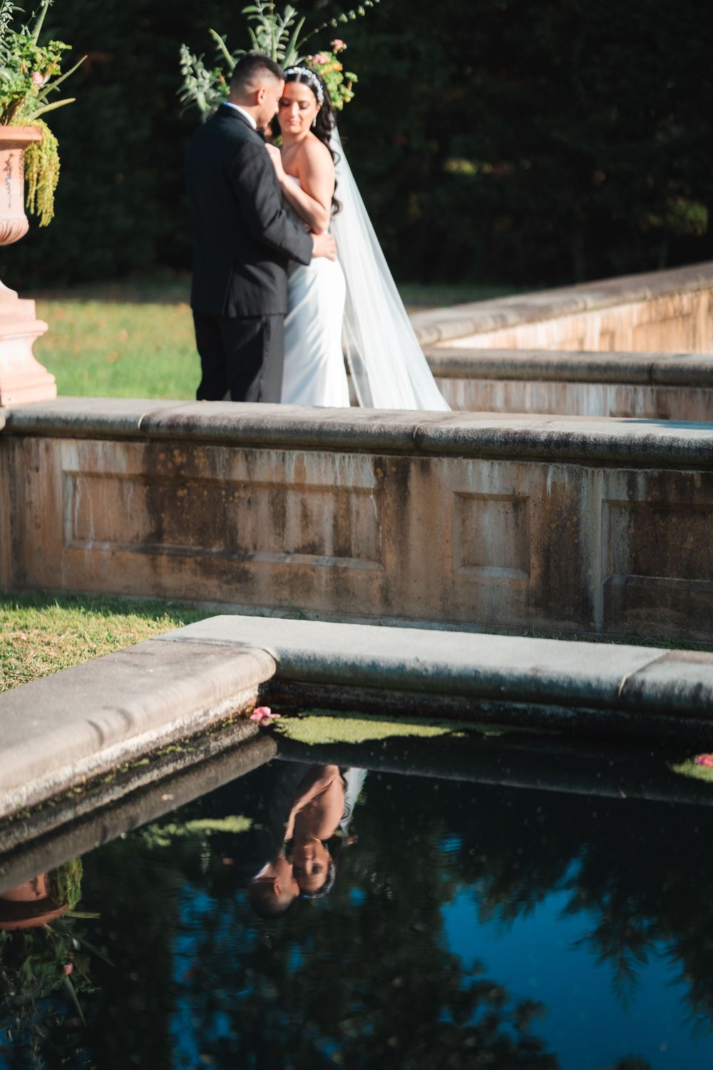 Romantic wedding photography by a reflective pool showing the couple's silhouette against blue water.