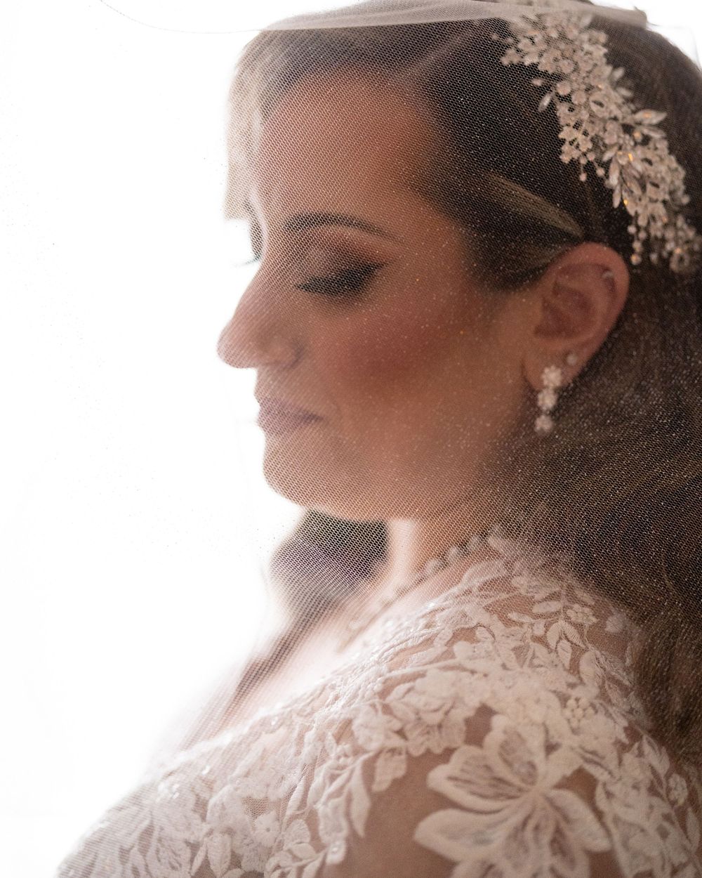 Soft-focus portrait showing delicate bridal hair accessories and lace details.