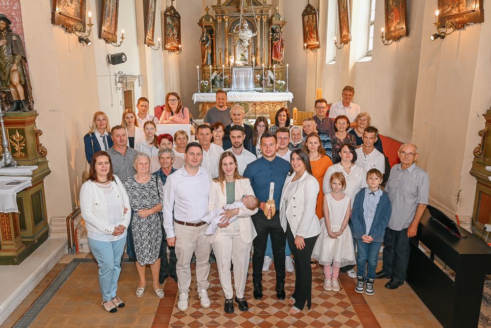 Large group of family and friends gathered inside a beautiful church with ornate religious decorations.