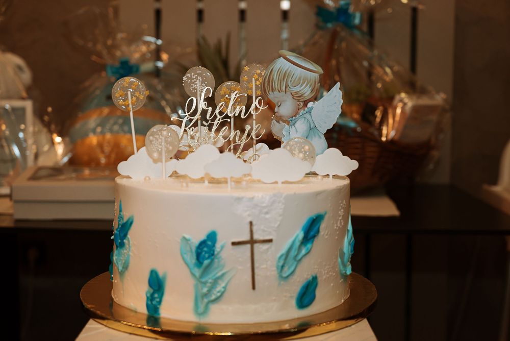 Elegant wedding cake decorated with white frosting, teal feather accents and crystal details at a reception venue.
