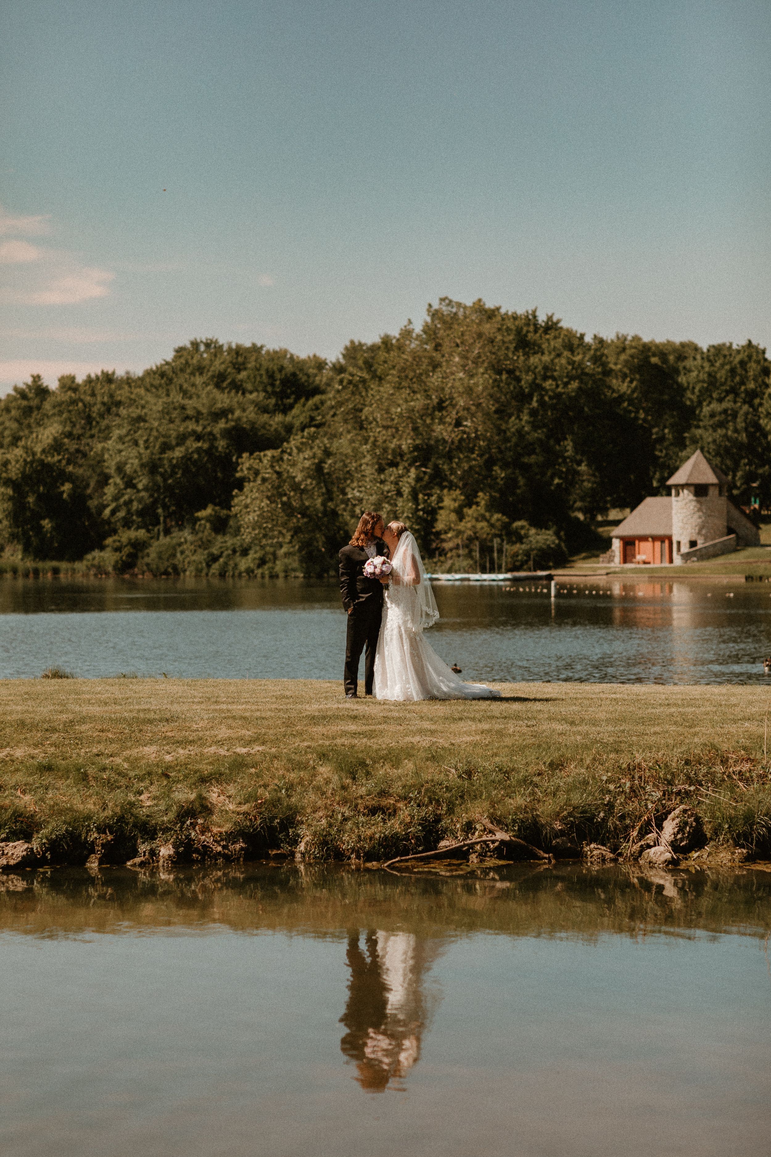 A romantic lakeside wedding portrait with the couple's reflection in the water.