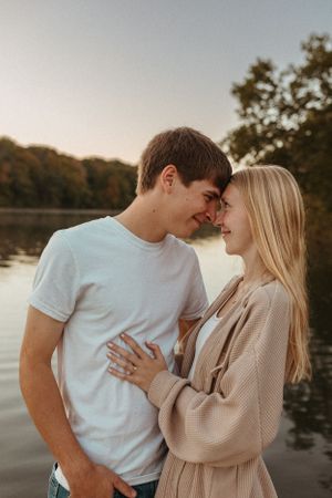 A romantic couple shares an intimate moment by a lake at sunset.
