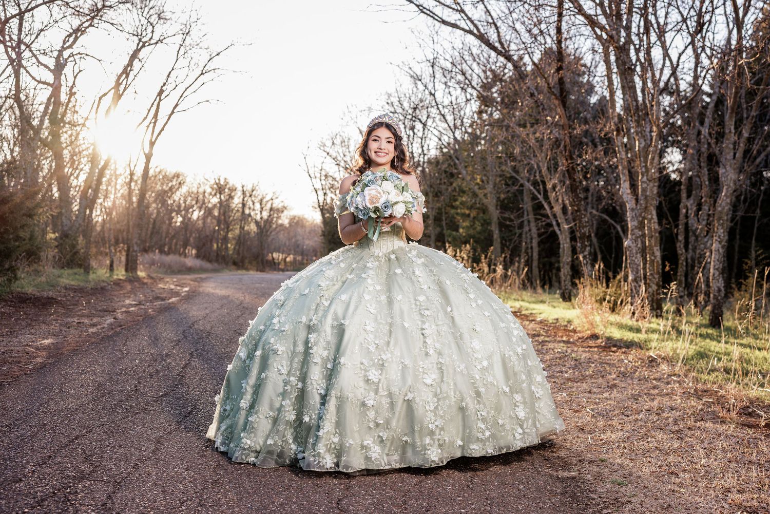 A shimmering white ball gown photographed on a nature path at golden hour.