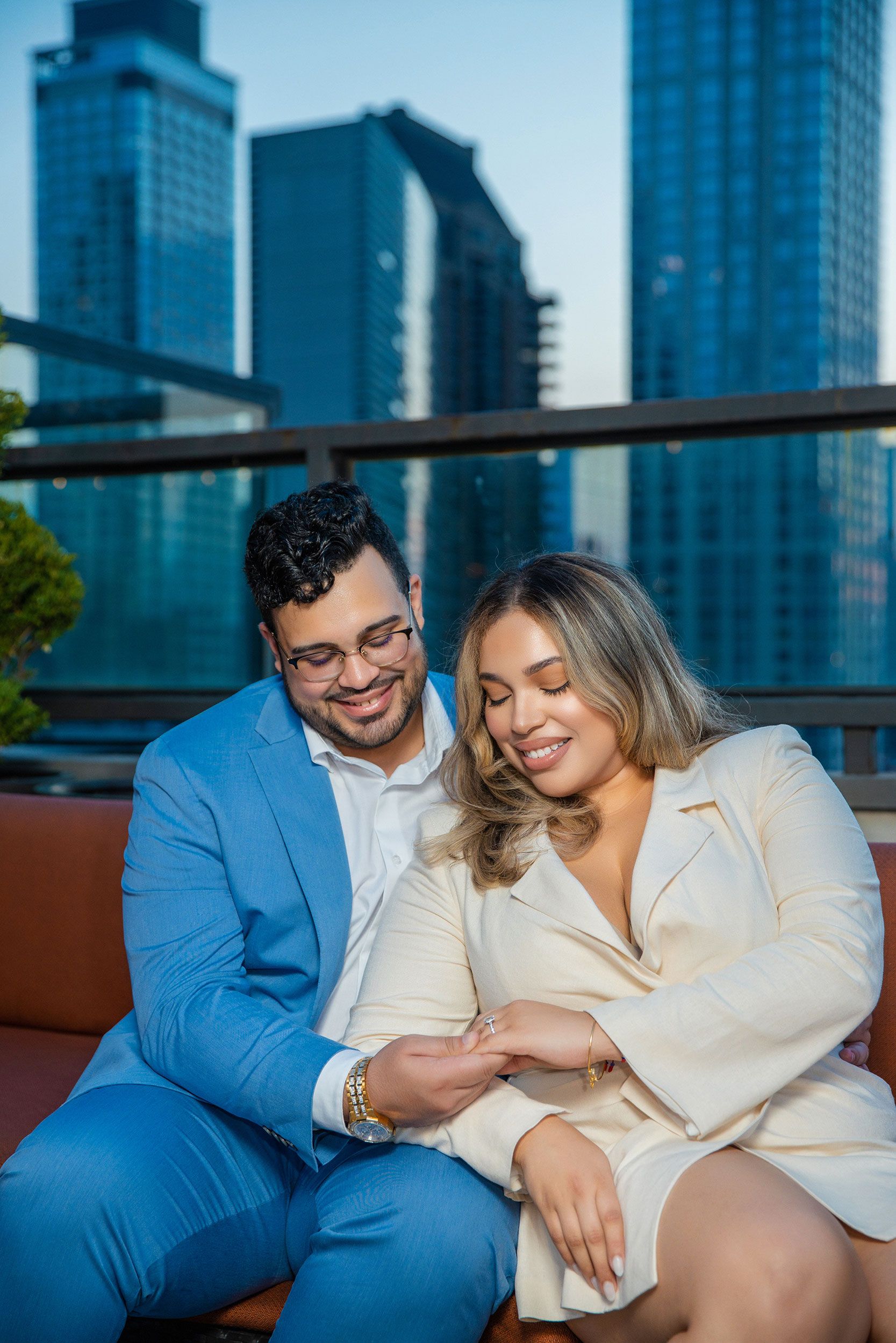 Couple enjoying romantic evening on rooftop terrace with urban skyline of high-rise buildings in background.