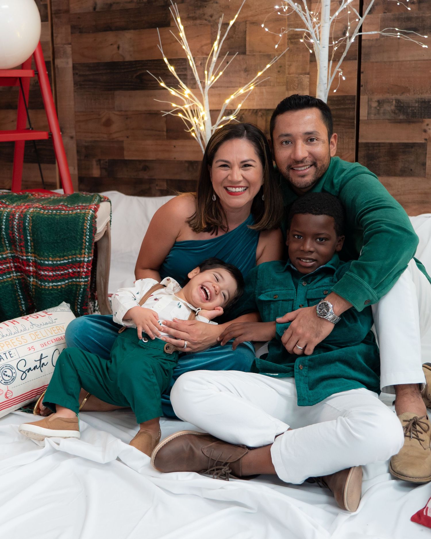 Family of four in matching teal outfits posing together for a festive Christmas photo session.